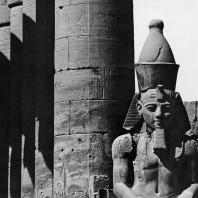 Луксор. Египет. Верхняя часть статуи Аменхотепа III, узурпированной Рамсесом II, на фоне прецессионной колоннады Аменхотепа III. Вид из первого двора. Фотограф: Анджей Дзевановский